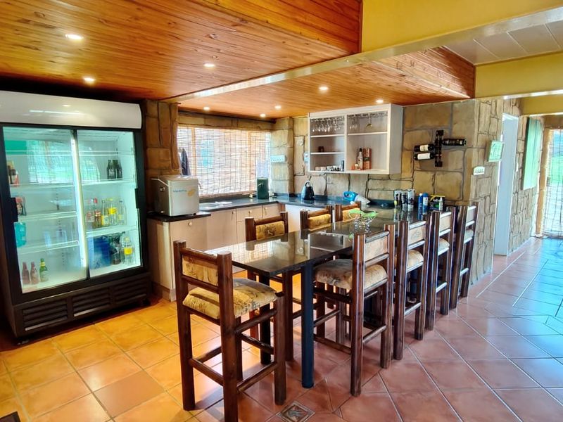 A rustic-style bar area featuring stone-clad walls, a timber-paneled ceiling, granite countertops, and tiled flooring, creating a warm and inviting entertainment space.