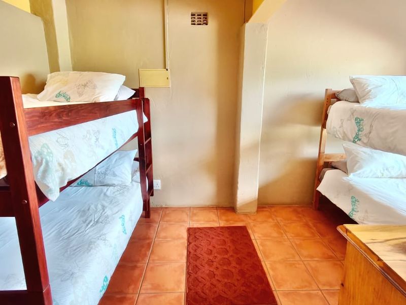 A functional bedroom featuring tiled flooring and neutral wall finishes, currently configured with two sets of bunk beds.
