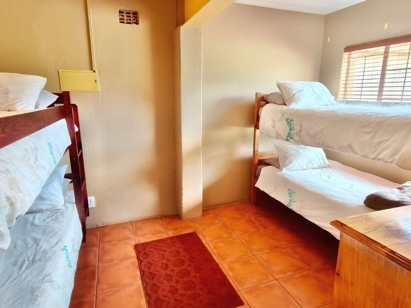 A functional bedroom featuring tiled flooring and venetian blinds, currently configured with two sets of bunk beds.