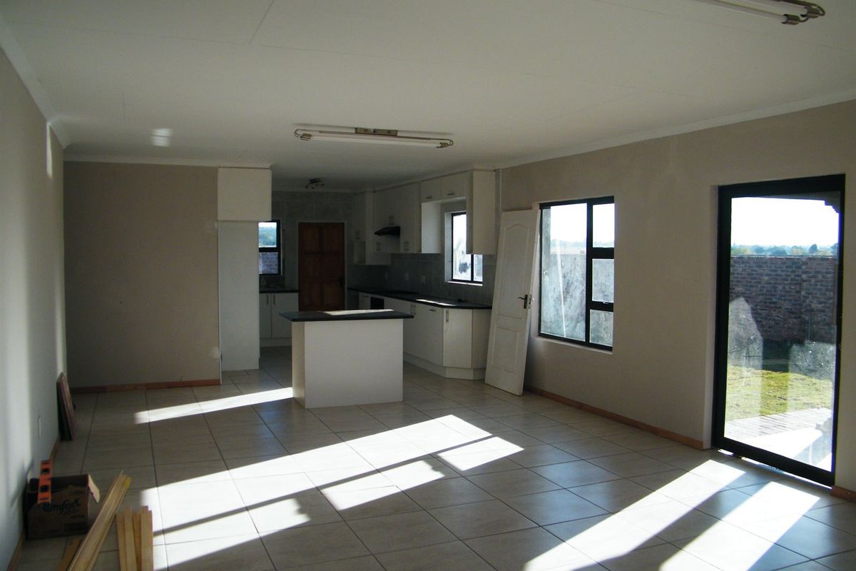 Open plan living and kitchen area featuring tiled flooring, built-in cabinetry, and direct access to the rear garden through a sliding glass door.