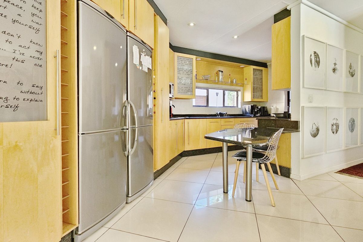 A functional kitchen featuring light wood cabinetry, dark granite countertops, and tiled flooring, offering a practical layout with integrated storage and workspace.