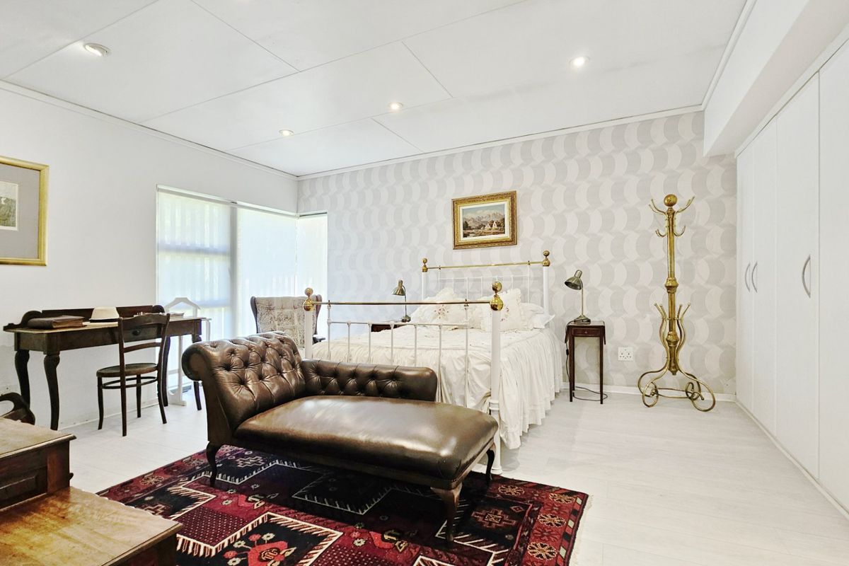 Spacious bedroom featuring built-in wardrobes, patterned wallpaper, and recessed downlighting, offering a clean and well-maintained living space.