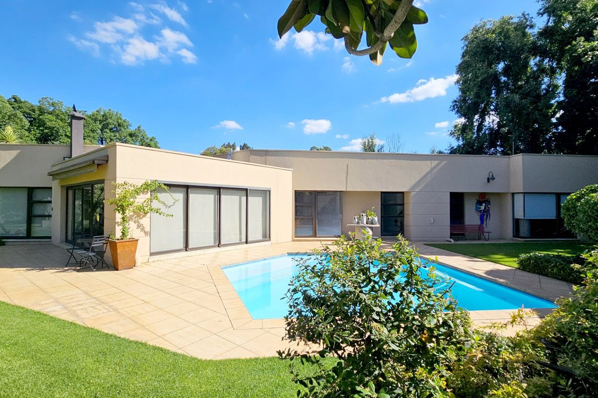 Rear view of the property featuring a swimming pool, paved patio area, and well-maintained garden with sliding door access to the home.