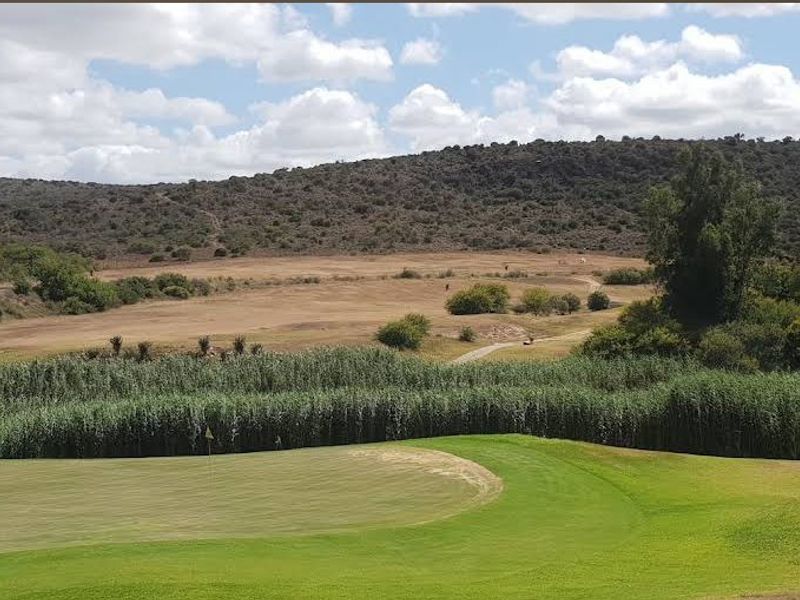 A scenic view overlooking a golf course fairway with natural rolling hills and native vegetation in the background.