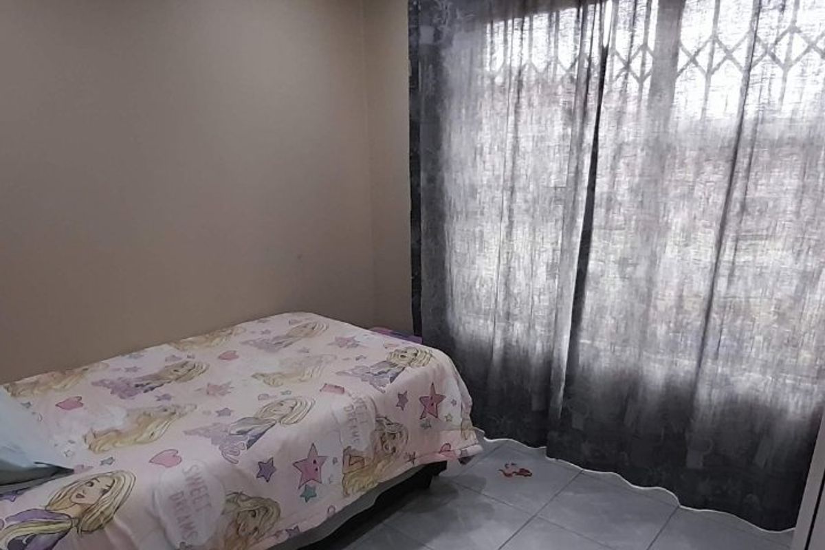 A standard bedroom featuring tiled flooring and a window fitted with a security gate.