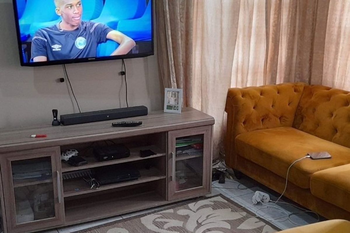 A cozy living room area featuring tiled flooring and a wall-mounted television setup.