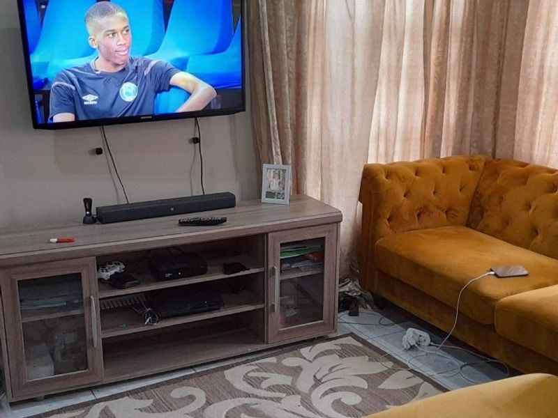 A cozy living room area featuring tiled flooring and a wall-mounted television setup.