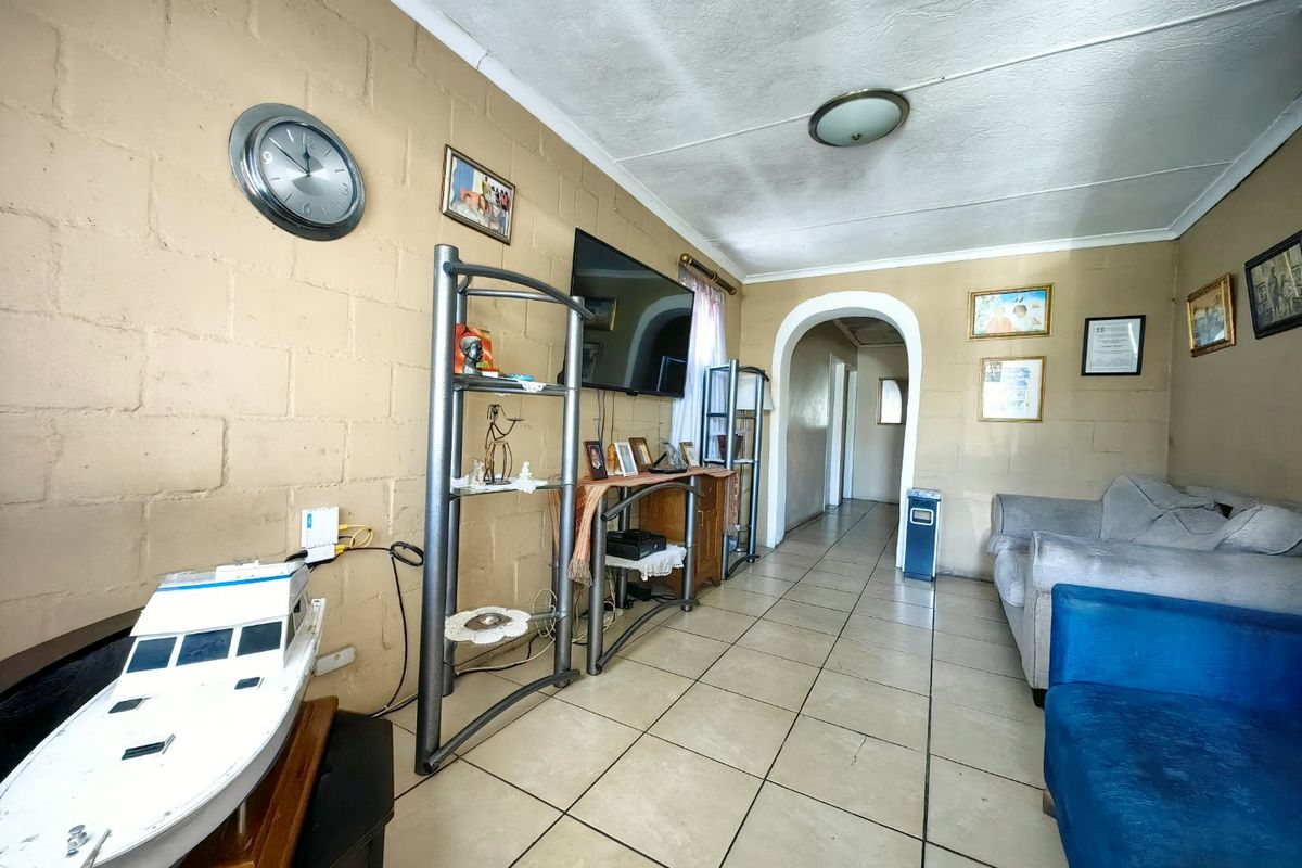 Living room featuring exposed blockwork walls, ceramic tiled flooring, and an arched entryway leading to the hallway.
