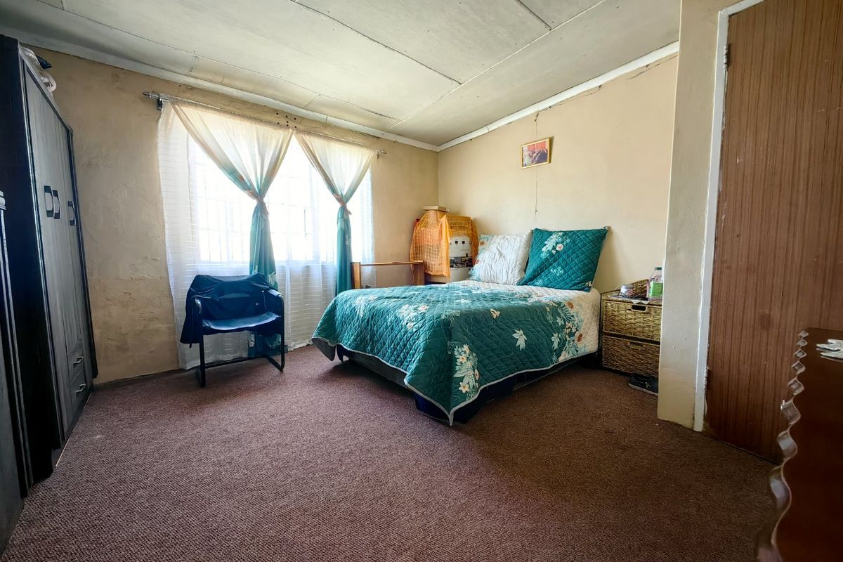 A bedroom featuring carpeted flooring and ceiling tiles, requiring cosmetic updates to the wall finishes and ceiling to improve its overall condition.