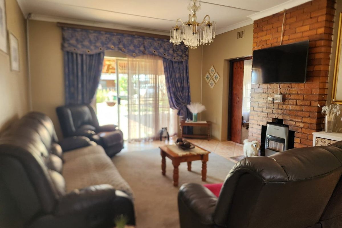 A comfortable living room featuring a prominent brick fireplace, a classic crystal chandelier, and sliding glass doors providing access to the outdoor area.