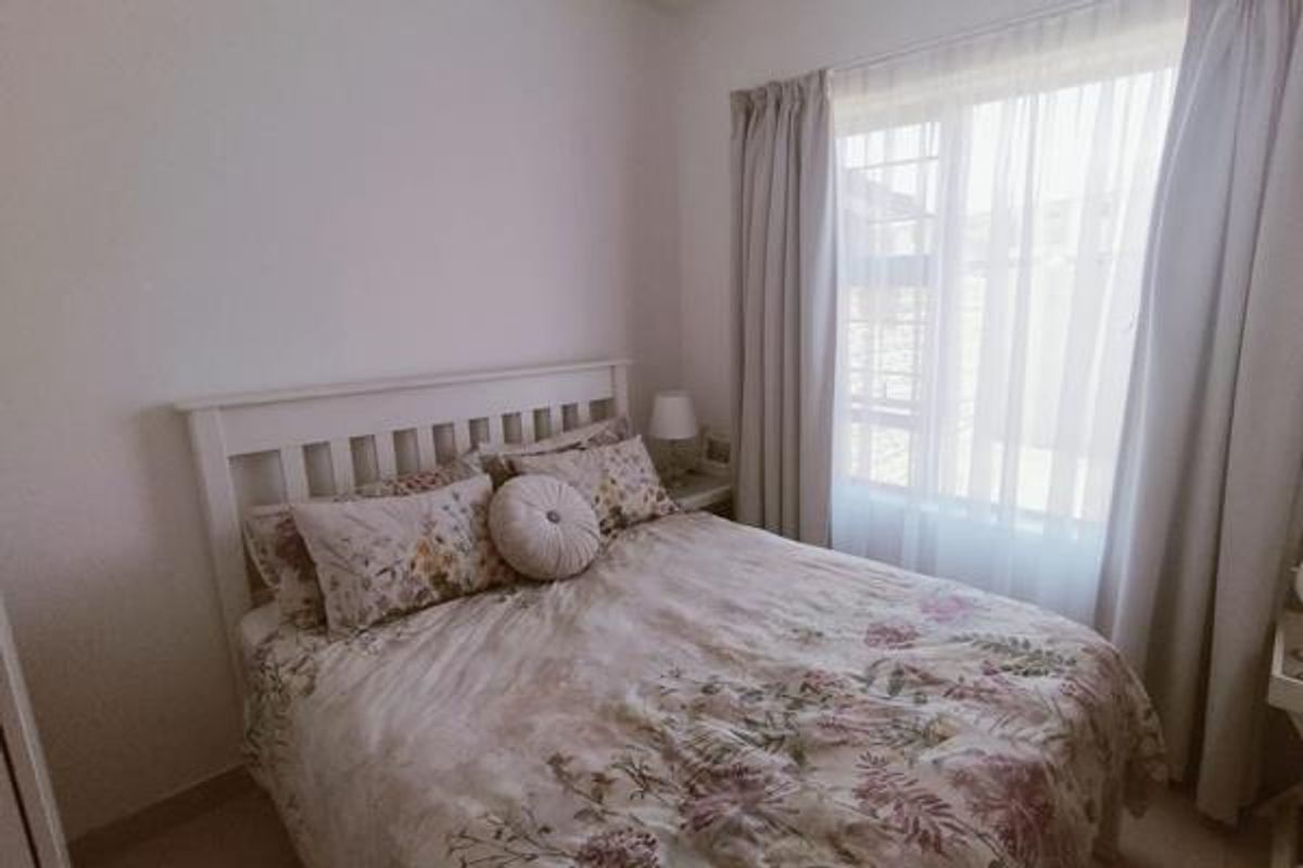 A cozy bedroom featuring a window with installed curtain tracks, providing natural light and a comfortable living space.