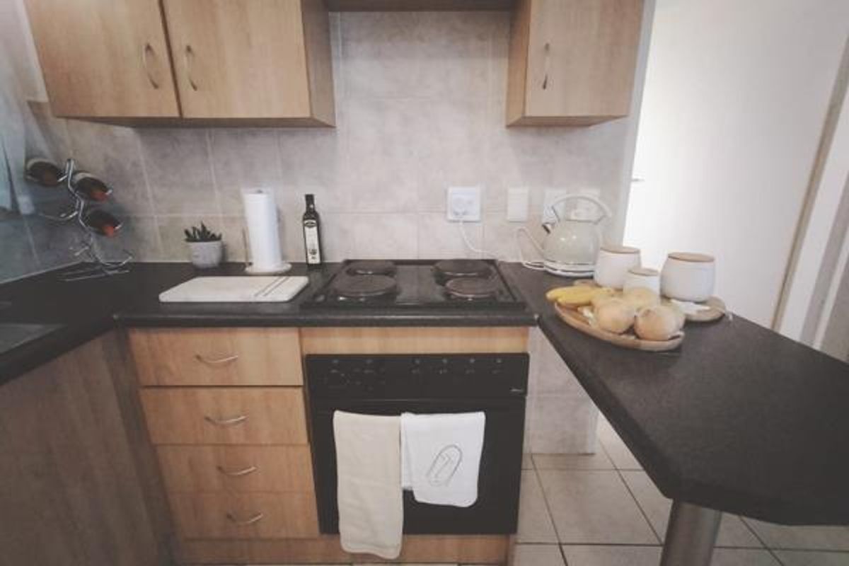 A functional kitchen featuring laminate cabinetry, a built-in oven with electric hob, tiled backsplash, and an integrated breakfast bar.