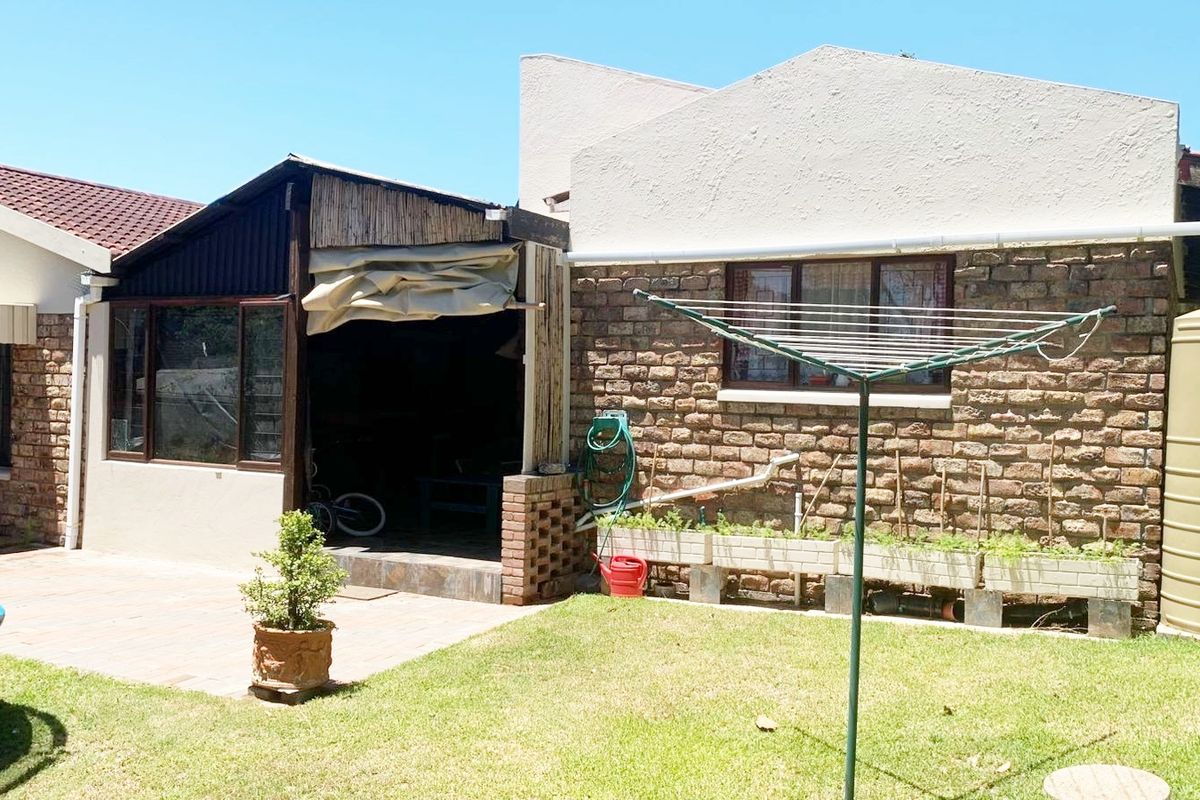 Rear exterior view of the property featuring a brick facade, paved patio area, and a large water storage tank.