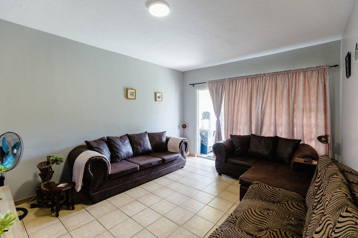 A comfortable living room featuring neutral tiled flooring and a sliding glass door providing access to an outdoor area.
