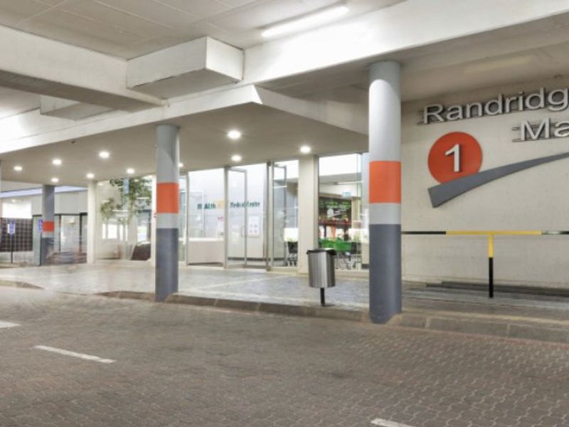 The front entrance of Randridge Mall featuring a covered paved driveway, structural columns, and clear glass access doors.