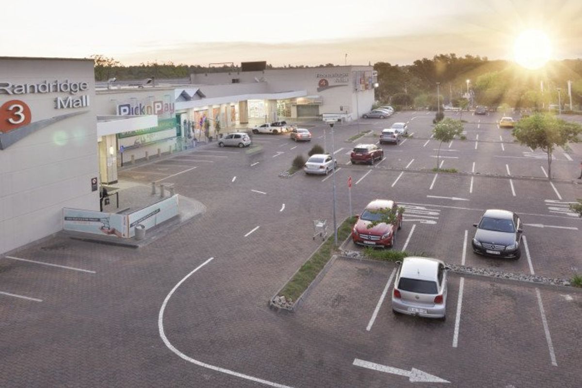Aerial view of a commercial shopping mall parking area with paved surfaces and marked parking bays.