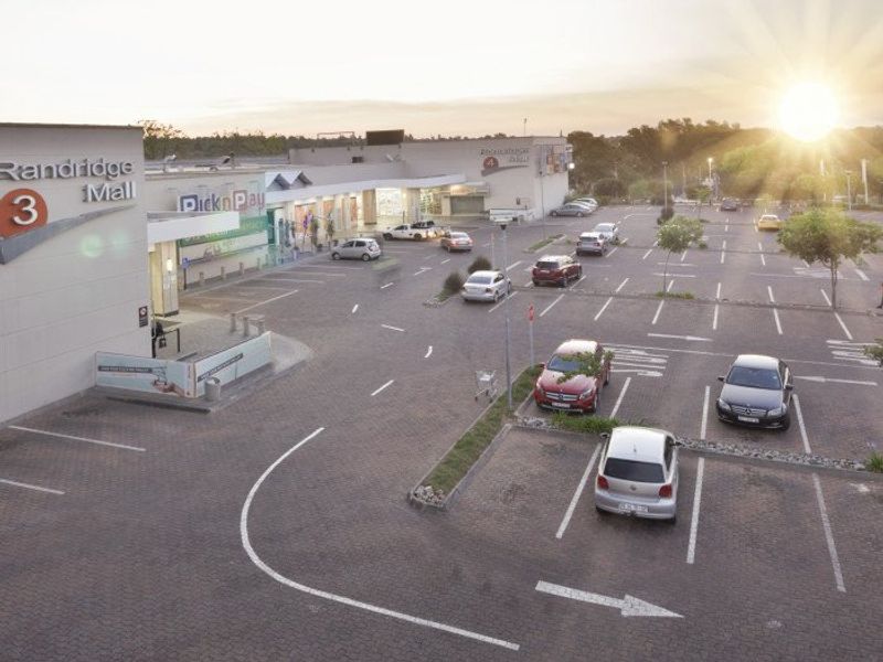 Aerial view of a commercial shopping mall parking area with paved surfaces and marked parking bays.