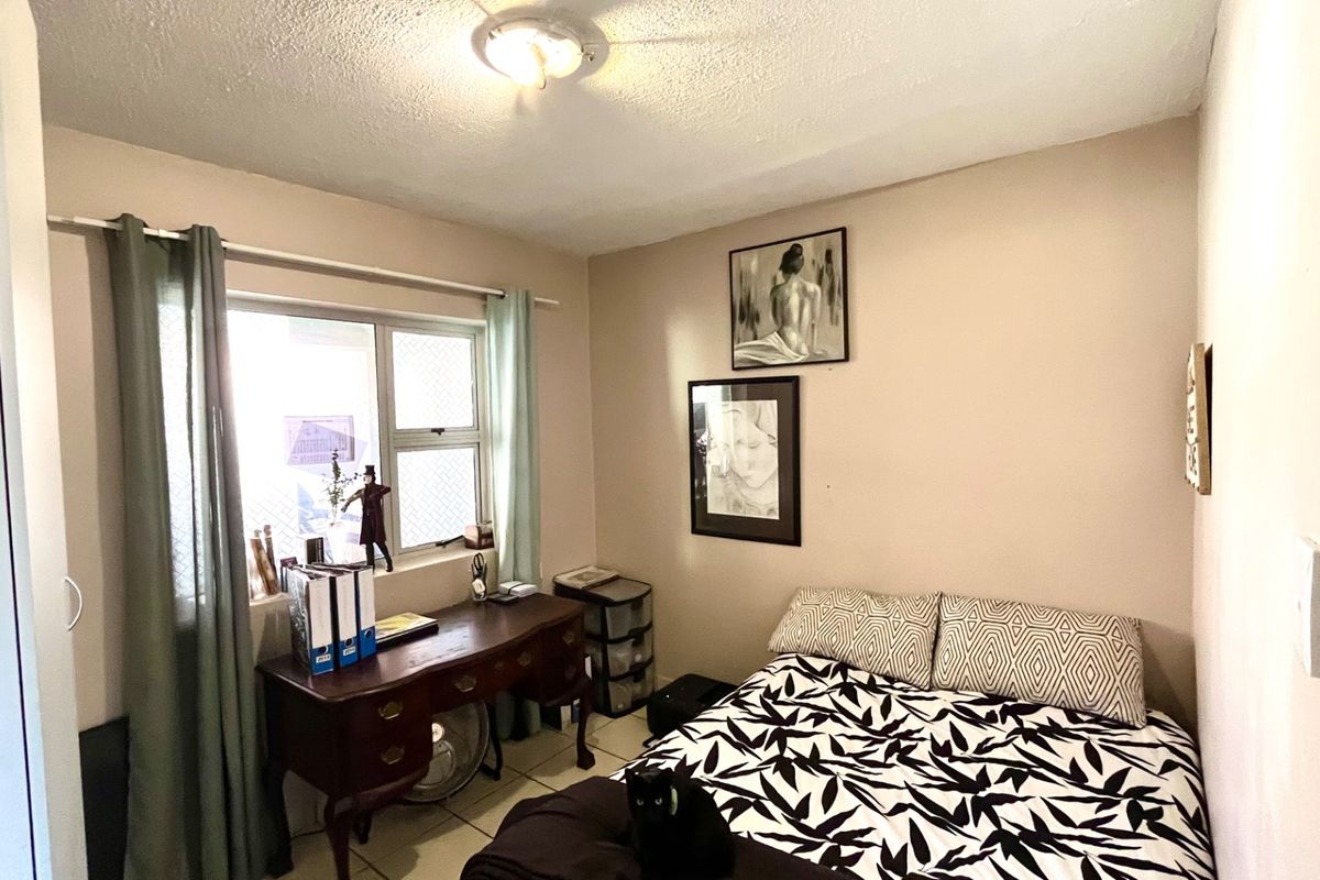 A functional bedroom featuring tiled flooring and a sliding window, providing a neutral space ready for personalization.