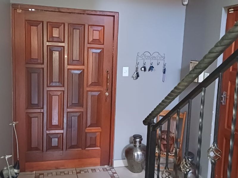 Entrance foyer featuring a solid timber front door, tiled flooring, and a decorative wrought iron staircase railing.