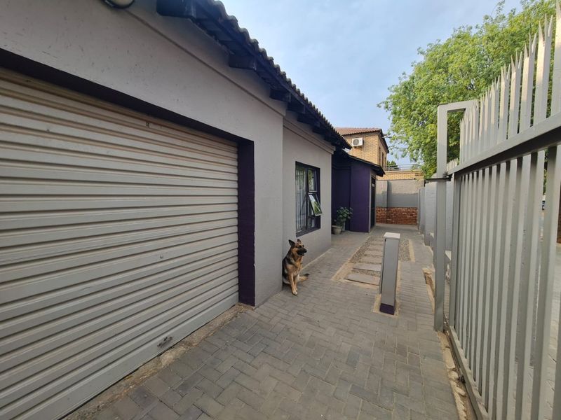 Exterior view of the property featuring a paved driveway, roller garage door, and secure metal perimeter fencing.