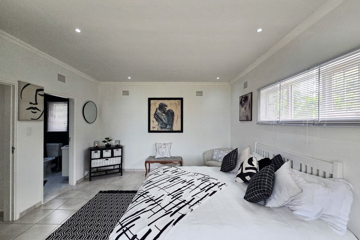 Spacious bedroom featuring tiled flooring, recessed downlighting, and an adjoining en-suite bathroom, presented in a clean and well-maintained condition.