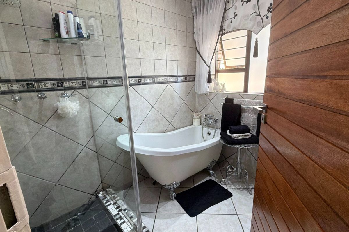 Bathroom featuring a classic clawfoot bathtub, a separate glass-enclosed shower, and neutral ceramic tiling throughout.