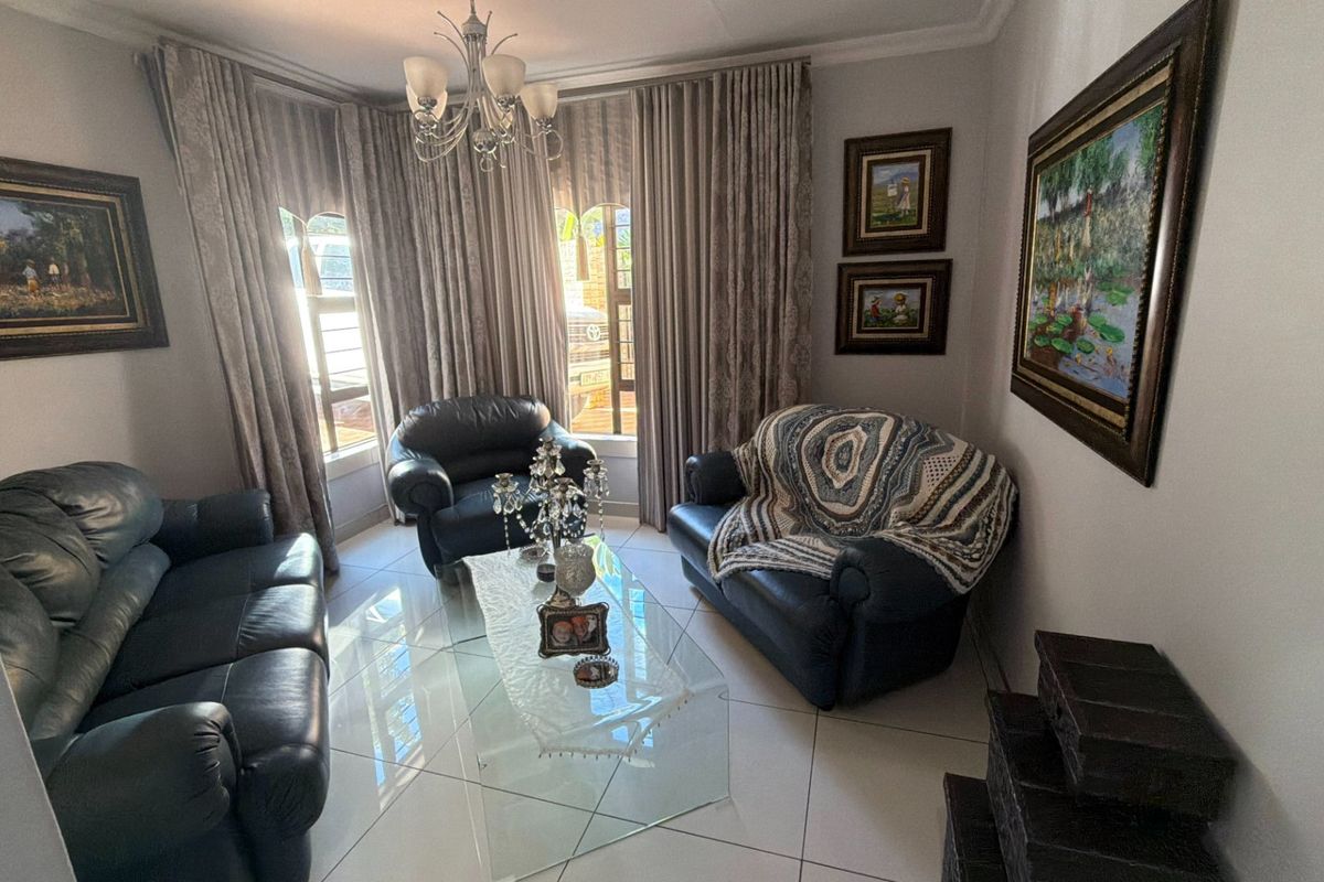 A well-maintained living room featuring large bay windows, tiled flooring, and decorative cove cornicing, providing a bright and comfortable space.