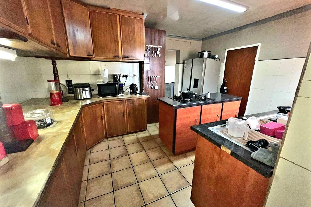 A functional kitchen featuring wooden cabinetry, laminate countertops, a built-in gas hob, and ceramic tile flooring, offering a traditional layout with ample storage space.