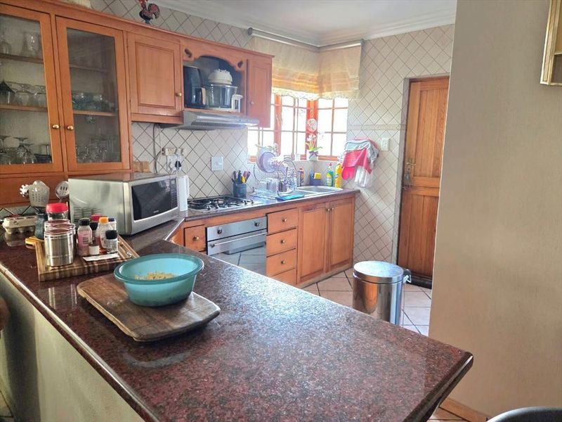 A functional kitchen featuring wooden cabinetry, granite countertops, a built-in oven, gas hob, and tiled backsplash, offering a classic layout with ample storage space.