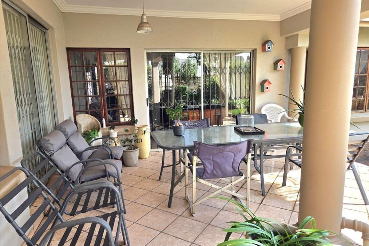 A covered patio area featuring tiled flooring, structural columns, and sliding glass doors providing access to the interior living space.