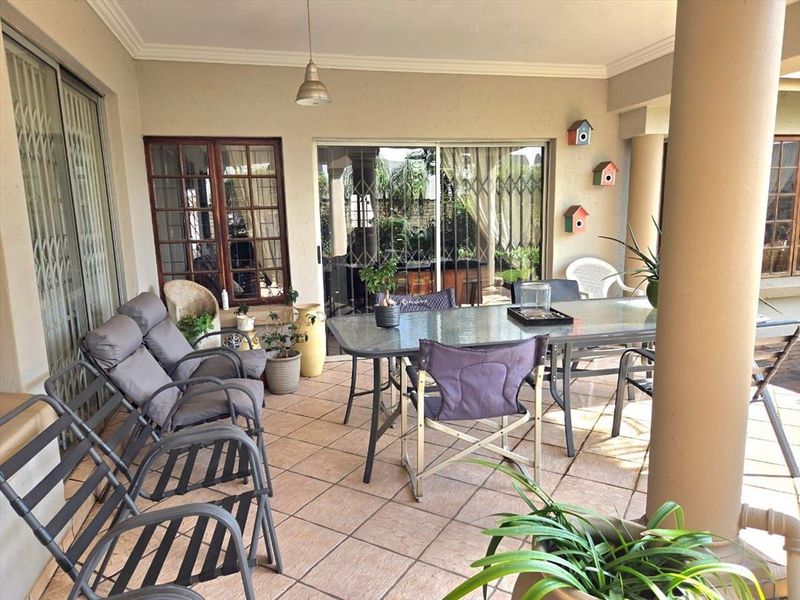 A covered patio area featuring tiled flooring, structural columns, and sliding glass doors providing access to the interior living space.