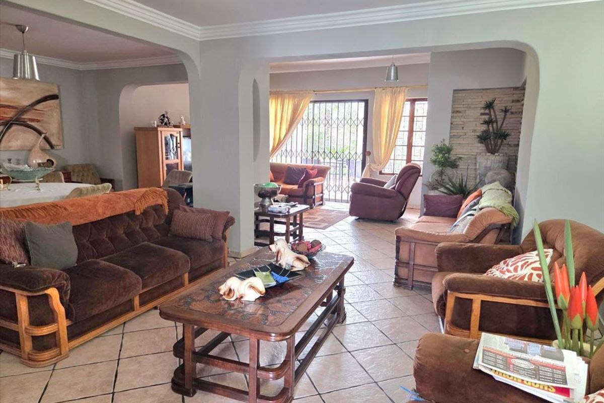 Spacious open-plan living area featuring tiled flooring, decorative crown molding, and arched transitions between connected living spaces.