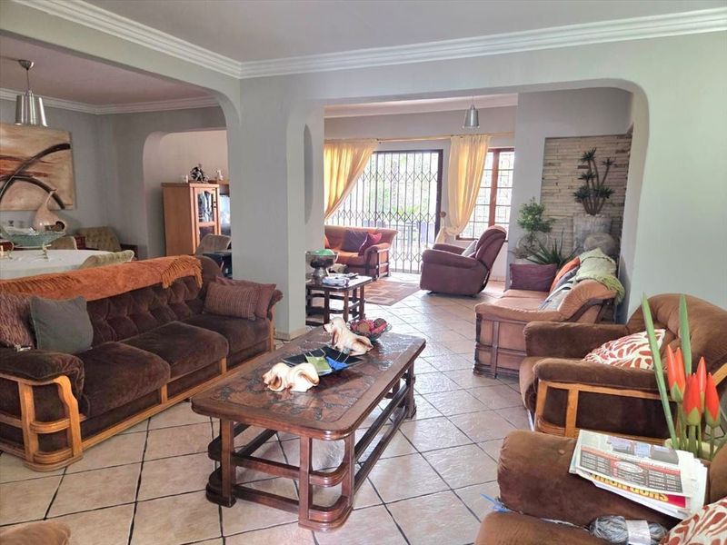 Spacious open-plan living area featuring tiled flooring, decorative crown molding, and arched transitions between connected living spaces.