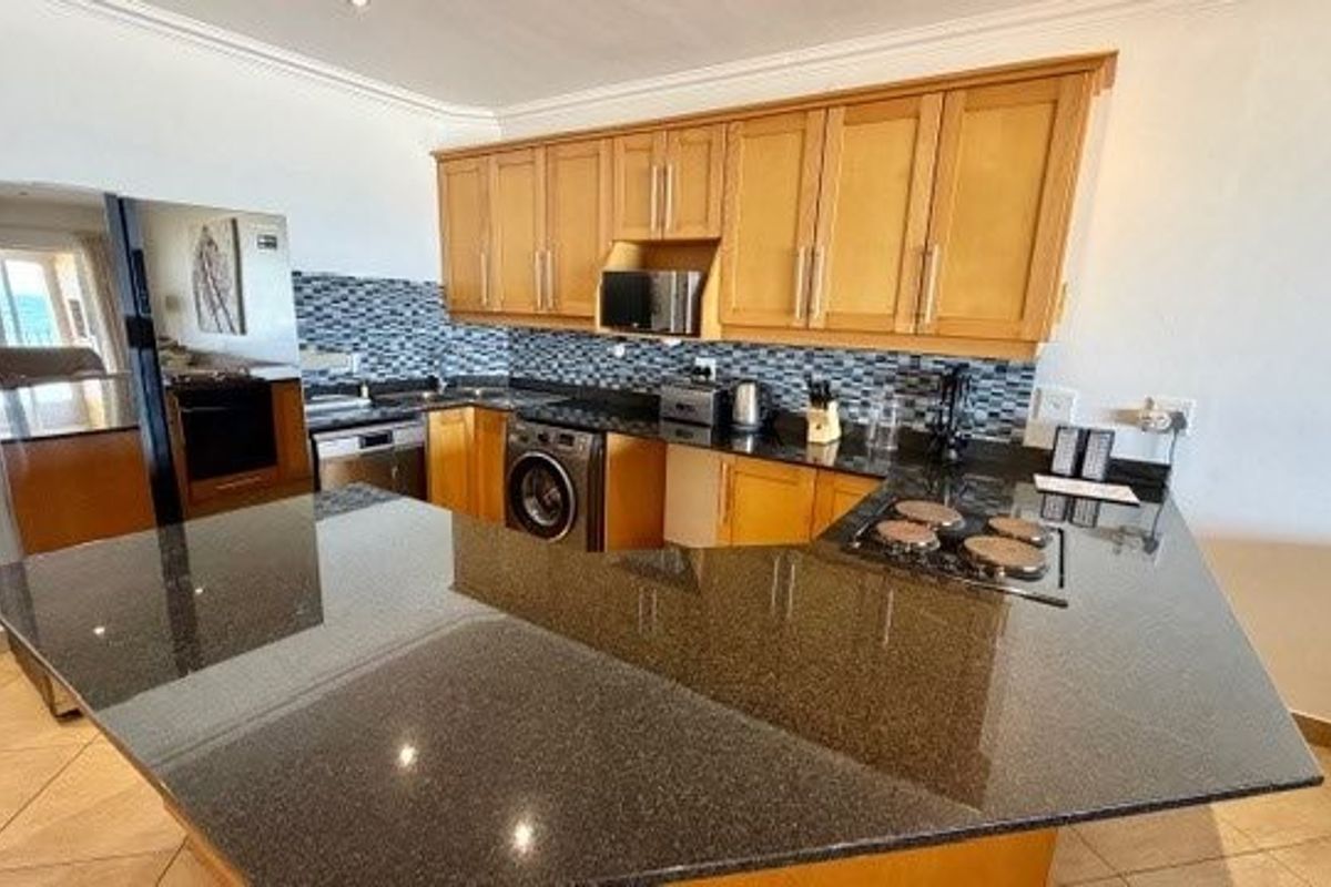 A functional kitchen featuring granite countertops, mosaic tile backsplash, and built-in cabinetry with integrated appliances and ceramic floor tiles.