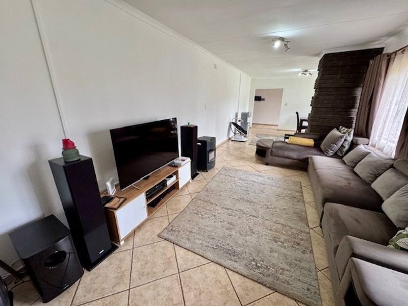 Spacious living room featuring tiled flooring and a prominent brick fireplace, offering a comfortable and functional layout for relaxation.