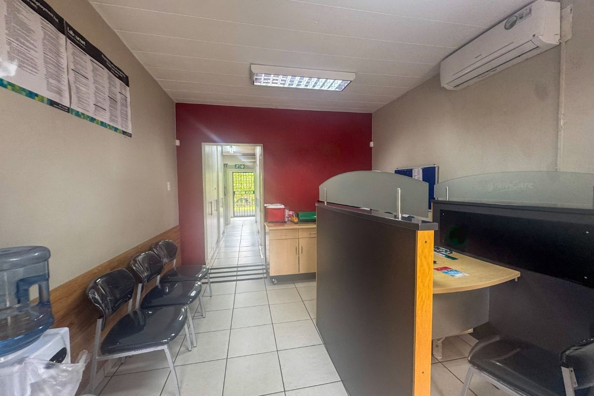 A functional commercial office space featuring tiled flooring, built-in partition walls, and a wall-mounted air conditioning unit.