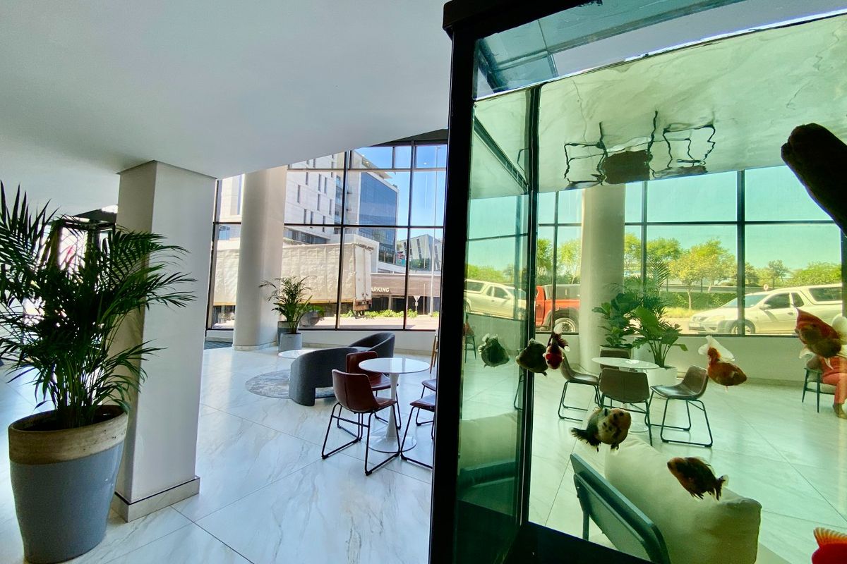 Modern open-plan commercial lobby featuring large format floor tiles and expansive floor-to-ceiling windows providing ample natural light and street views.