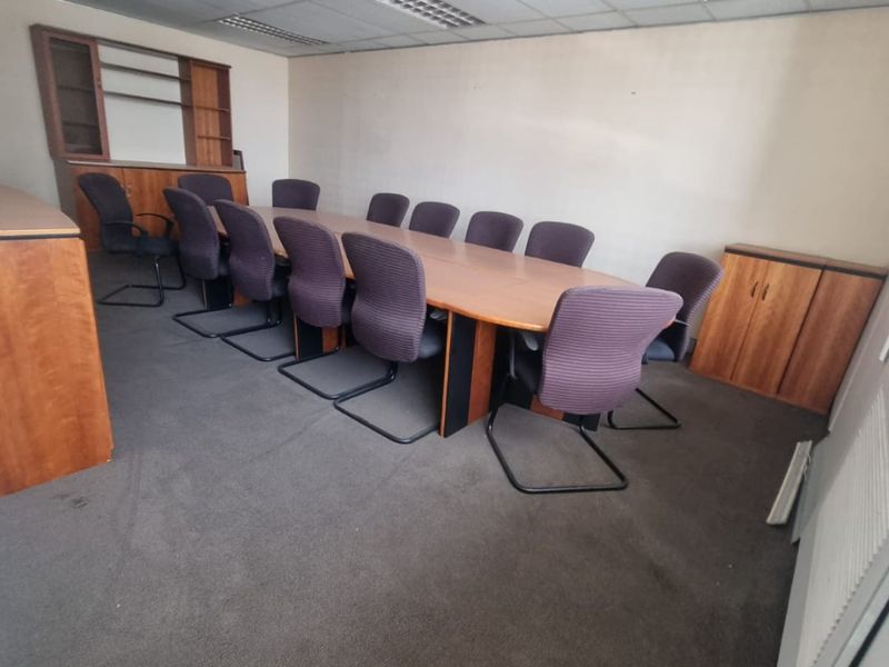 A functional office boardroom featuring a suspended ceiling, recessed lighting, built-in storage cabinetry, and carpeted flooring.
