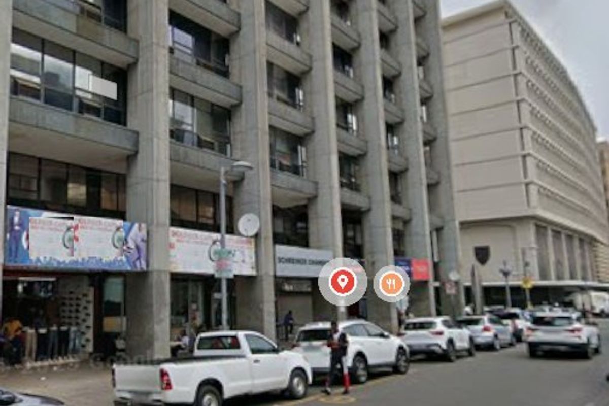 Street-level view of a multi-story commercial building featuring ground-floor retail storefronts and concrete architectural detailing.