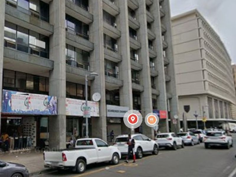 Street-level view of a multi-story commercial building featuring ground-floor retail storefronts and concrete architectural detailing.