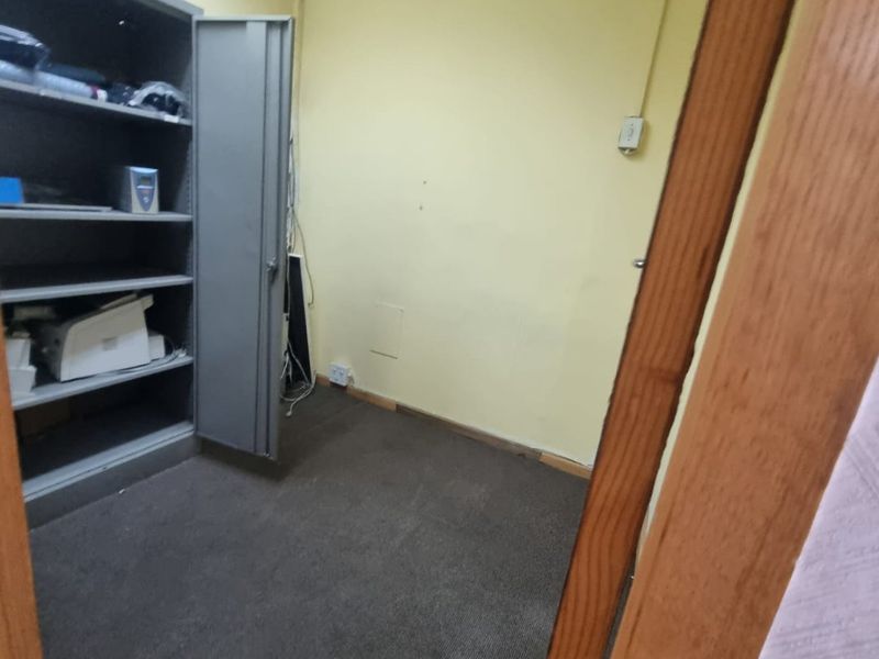 A small, vacant office space featuring carpeted flooring and a suspended ceiling, suitable for a private workspace or storage area.