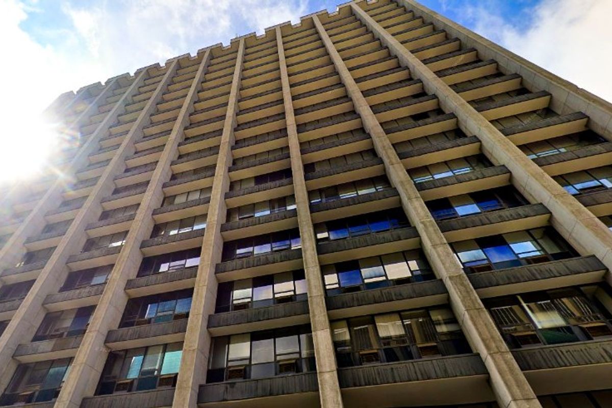 Low angle view of a multi-story commercial building facade featuring a repetitive concrete grid structure and integrated window panels.