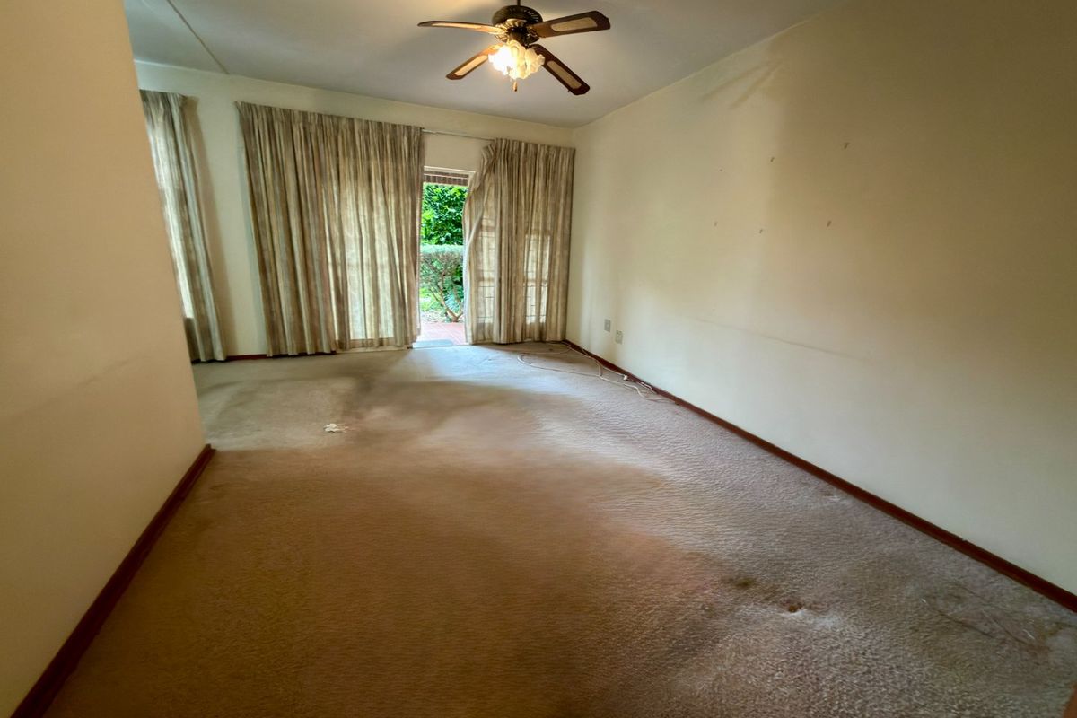 Spacious living room featuring a ceiling fan and large sliding glass doors that provide direct access to the outdoor garden area.