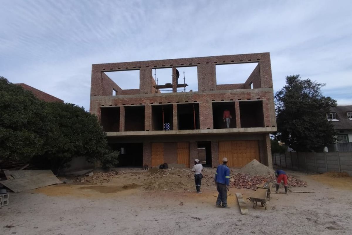A multi-story commercial building currently under construction, showing exposed brickwork and structural framing on a site with ongoing development work.