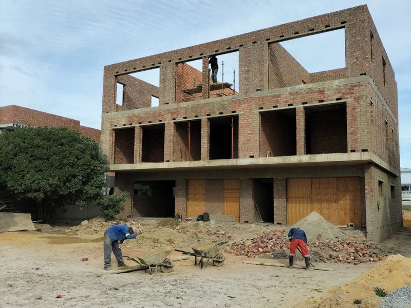 A multi-story commercial building under construction, featuring exposed brickwork and structural framing on a site currently undergoing development.
