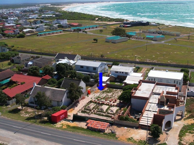 Aerial view of a coastal commercial property development site featuring vacant land and ongoing construction work near the ocean.