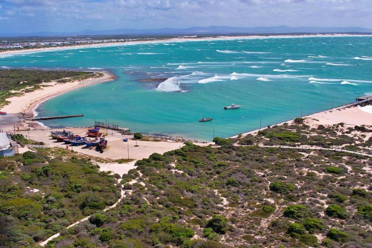 Aerial view of the coastal property featuring a jetty, sandy beach access, and expansive ocean views.
