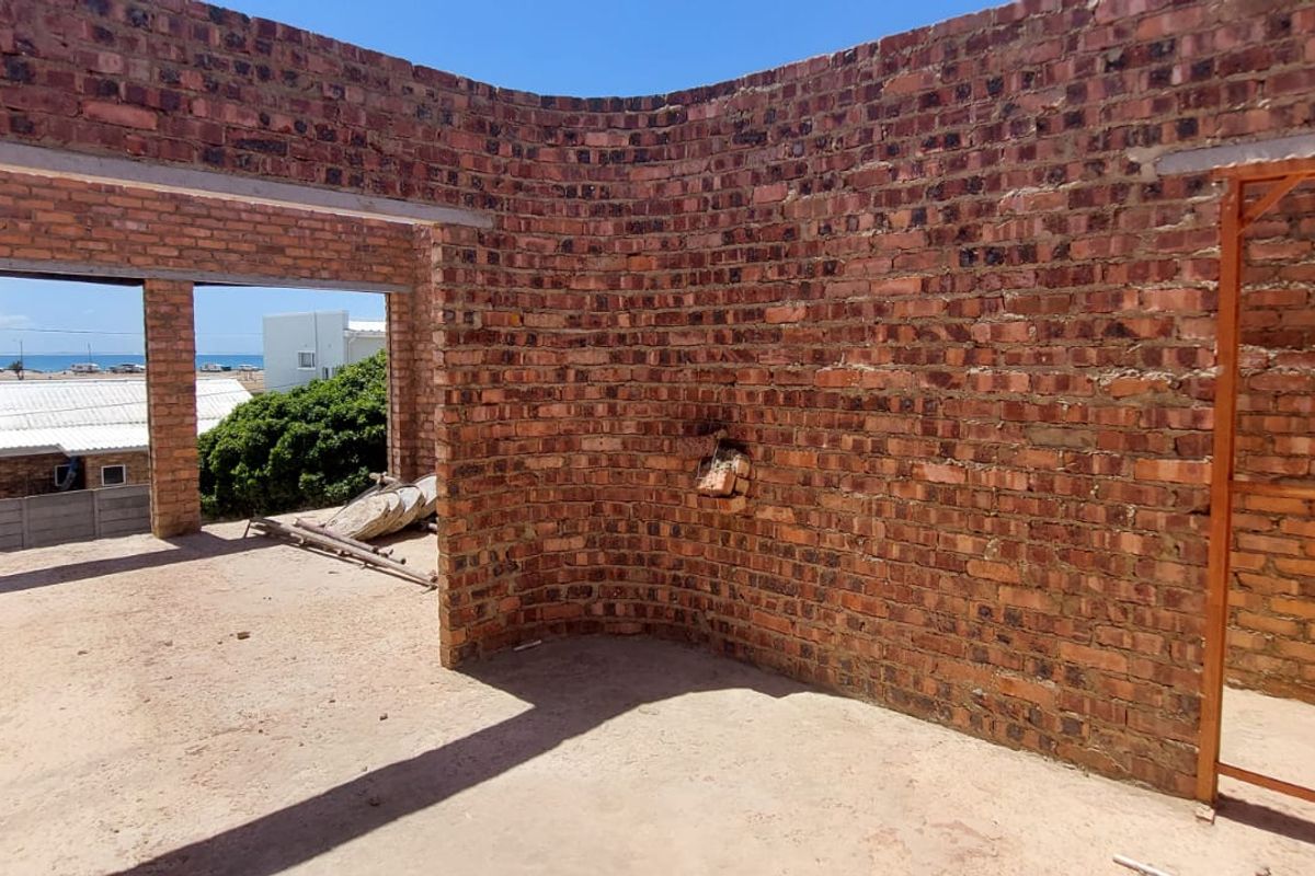 An unfinished open-plan interior space featuring exposed brick walls and concrete flooring, currently in a shell construction state.