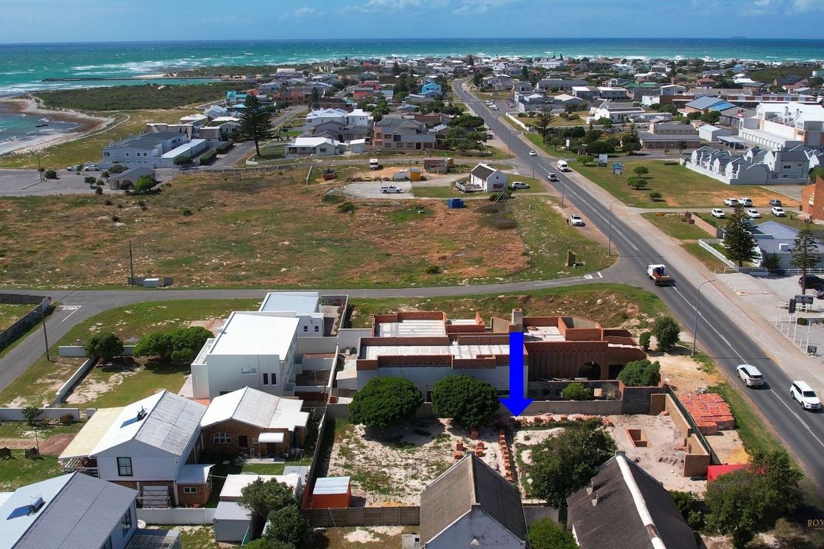 Aerial view of a coastal property under construction, showing the building footprint, surrounding boundary walls, and proximity to the ocean and main road.