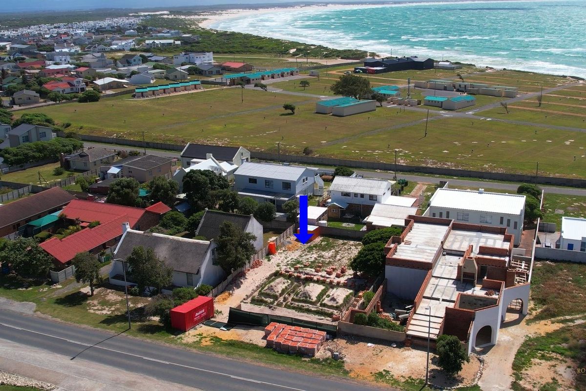 Aerial view of a coastal vacant plot situated in a residential area, offering proximity to the beach and surrounding neighborhood infrastructure.